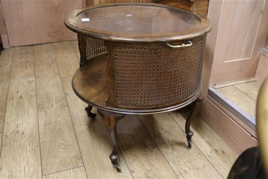An oval mahogany framed two tier coffee table with plate glass top and caned sides, W.65cm